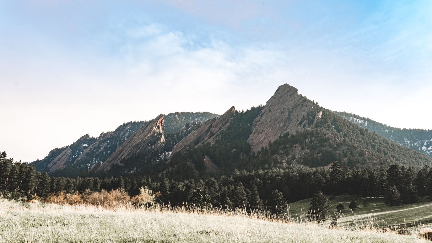 The Flatirons above Boulder in low golden light over a frosted meadow