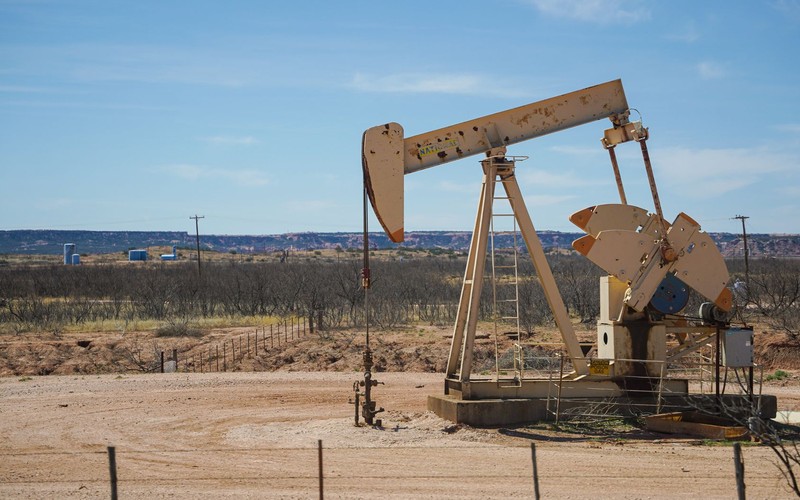 A pumpjack working alone on dry high desert ground, the kind of remote energy site a crew drives out to