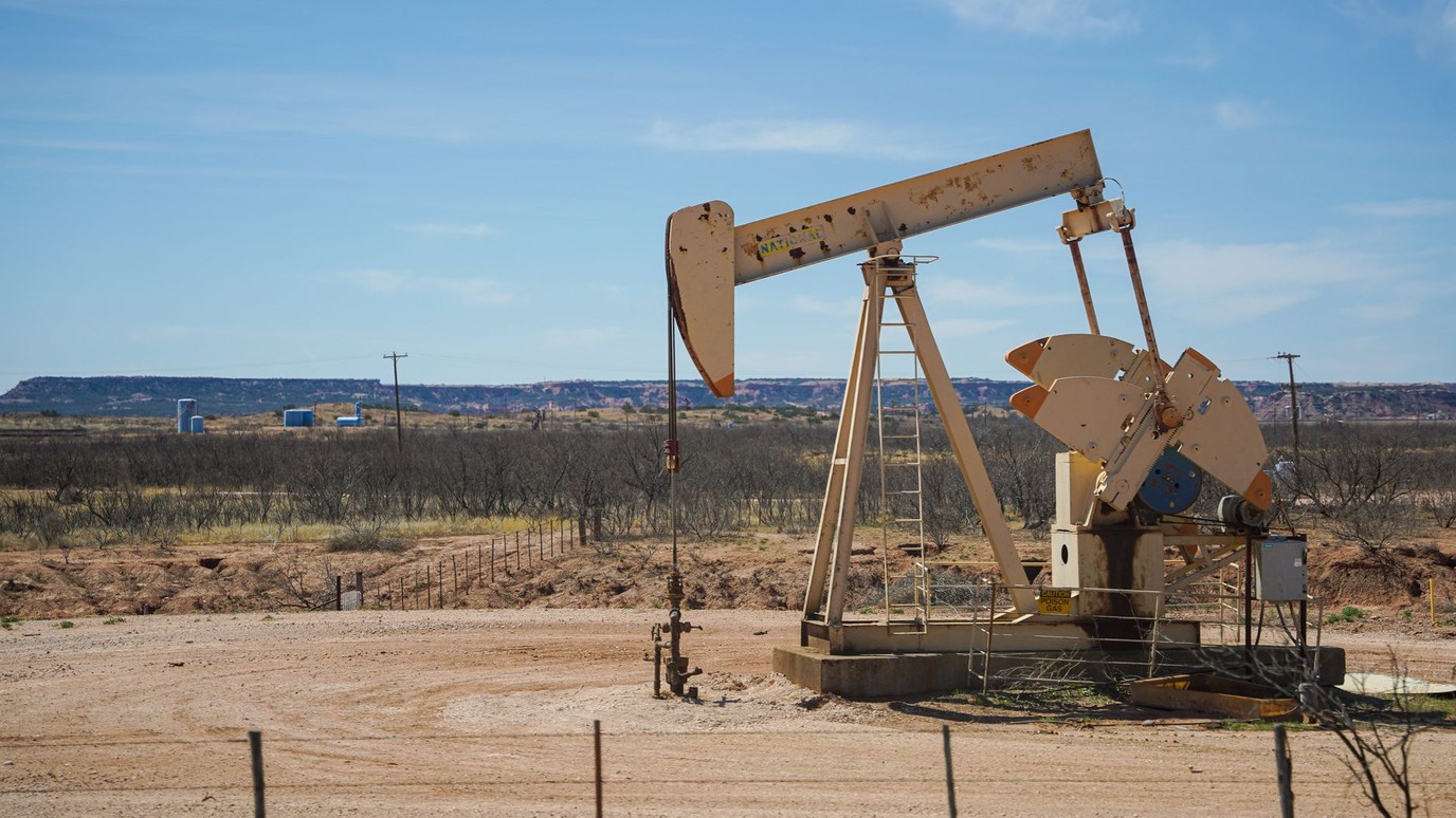A pumpjack working alone on dry high desert ground, the kind of remote energy site a crew drives out to