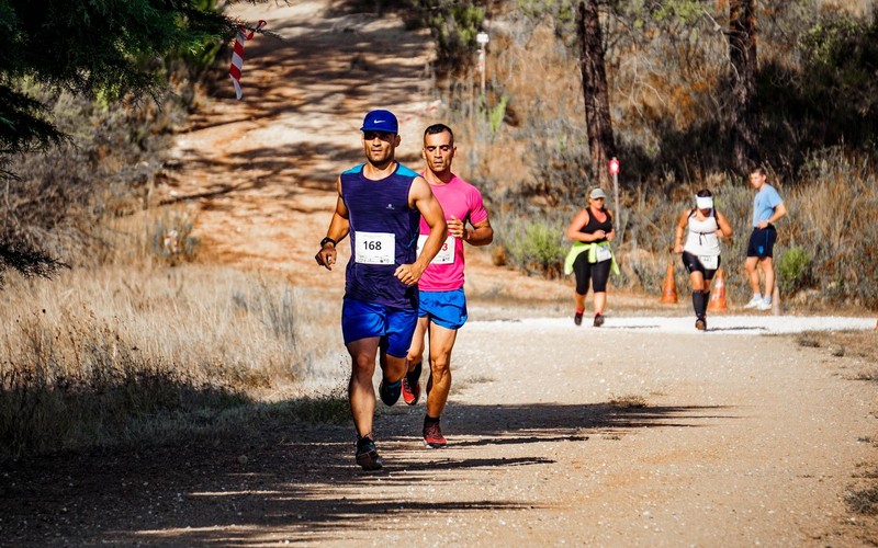 Runners wearing race bibs strung out along a dry mountain trail
