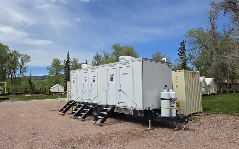 Combo shower trailer set at a base camp of canvas wall tents